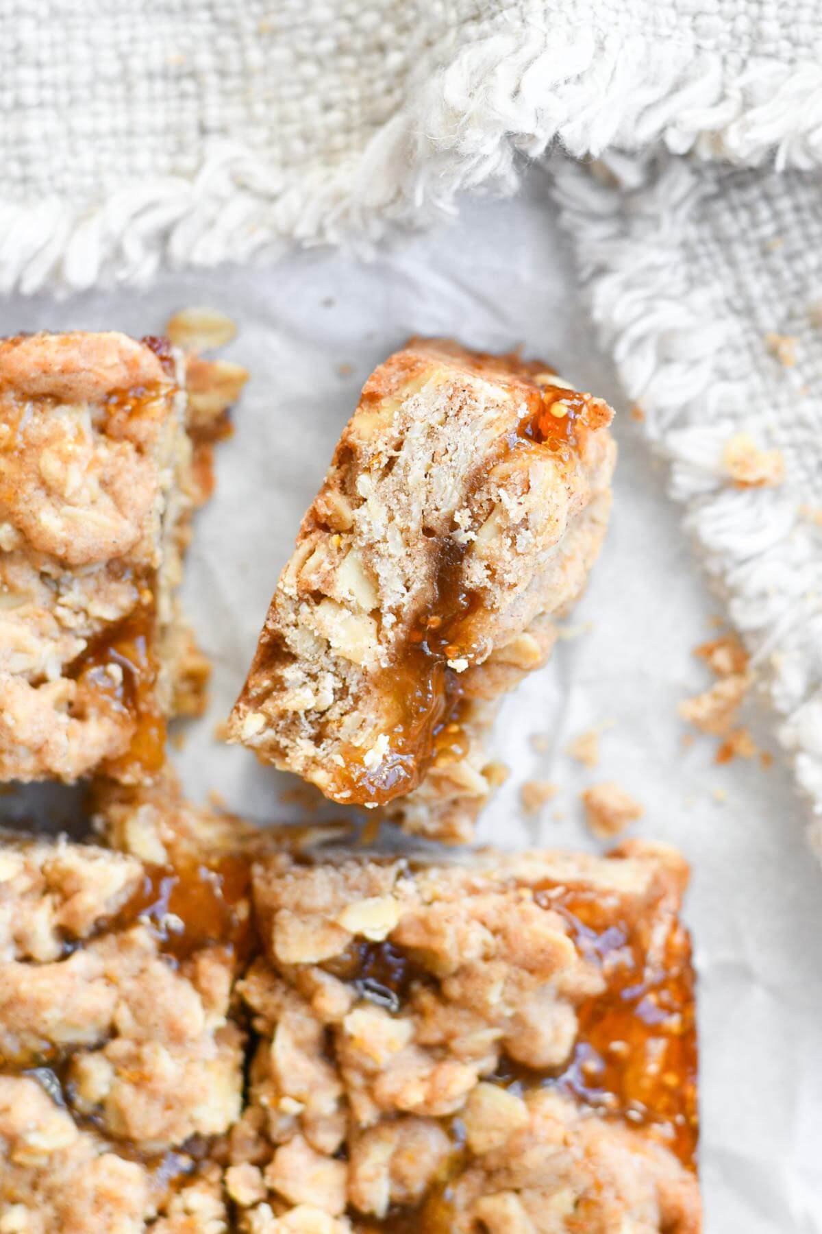 oatmeal fig bars cut into squares on white parchment paper.