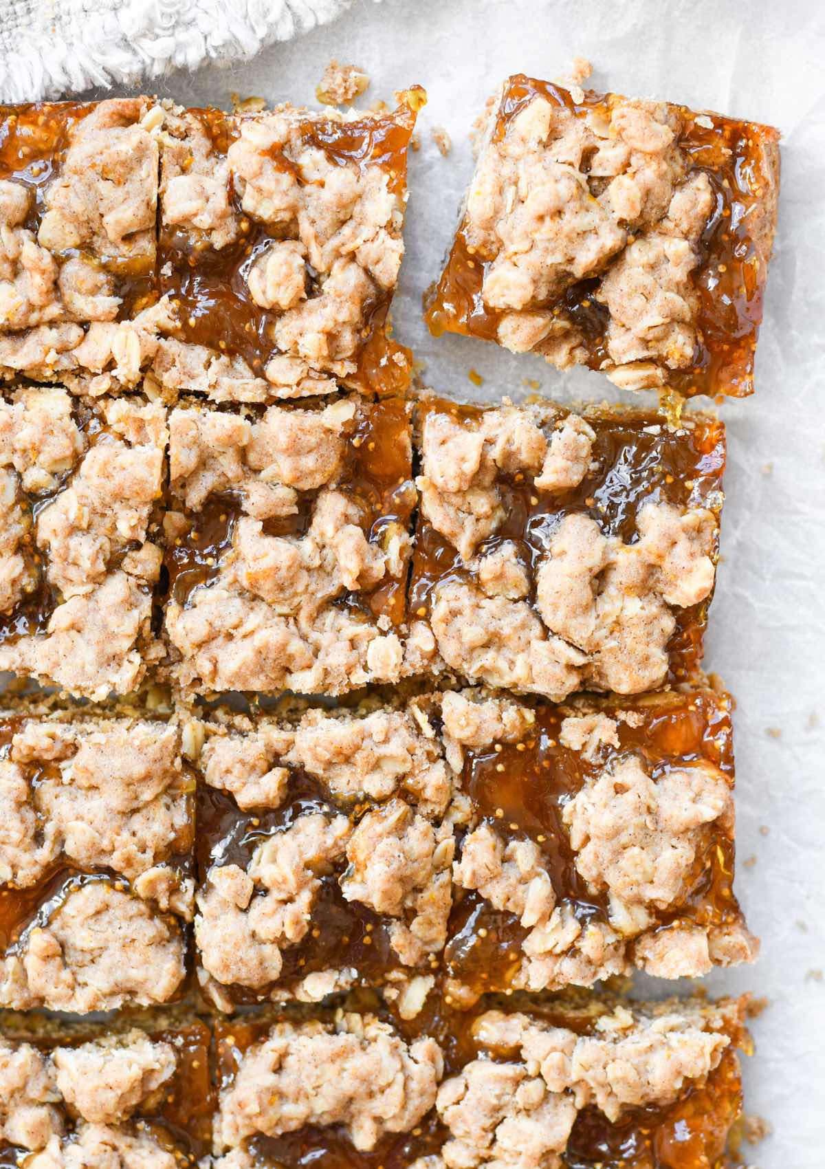 oatmeal fig bars cut into squares on white parchment paper.
