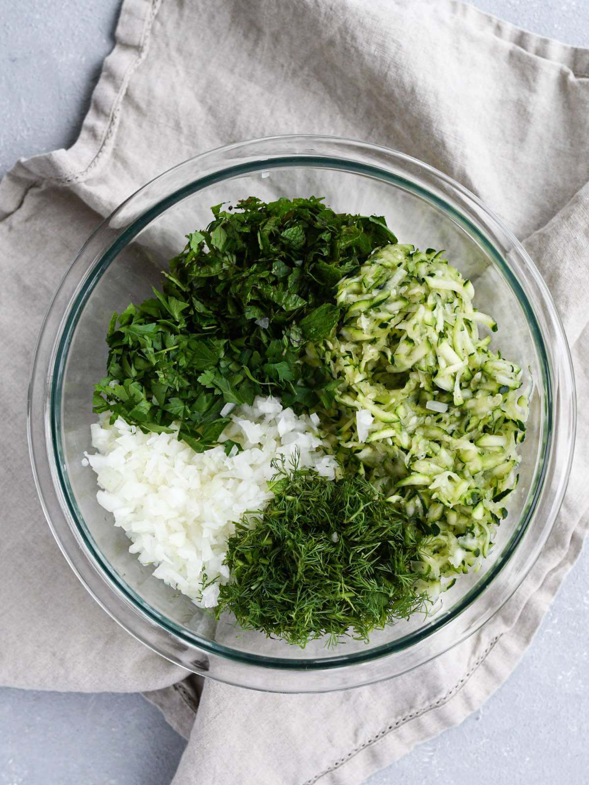 diced parsley, mint, onions, grated zucchini, and dill in a large glass bowl.