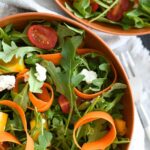 arugula salad with ribbon carrots, cherry tomatoes, crumbled goat cheese, and bell peppers