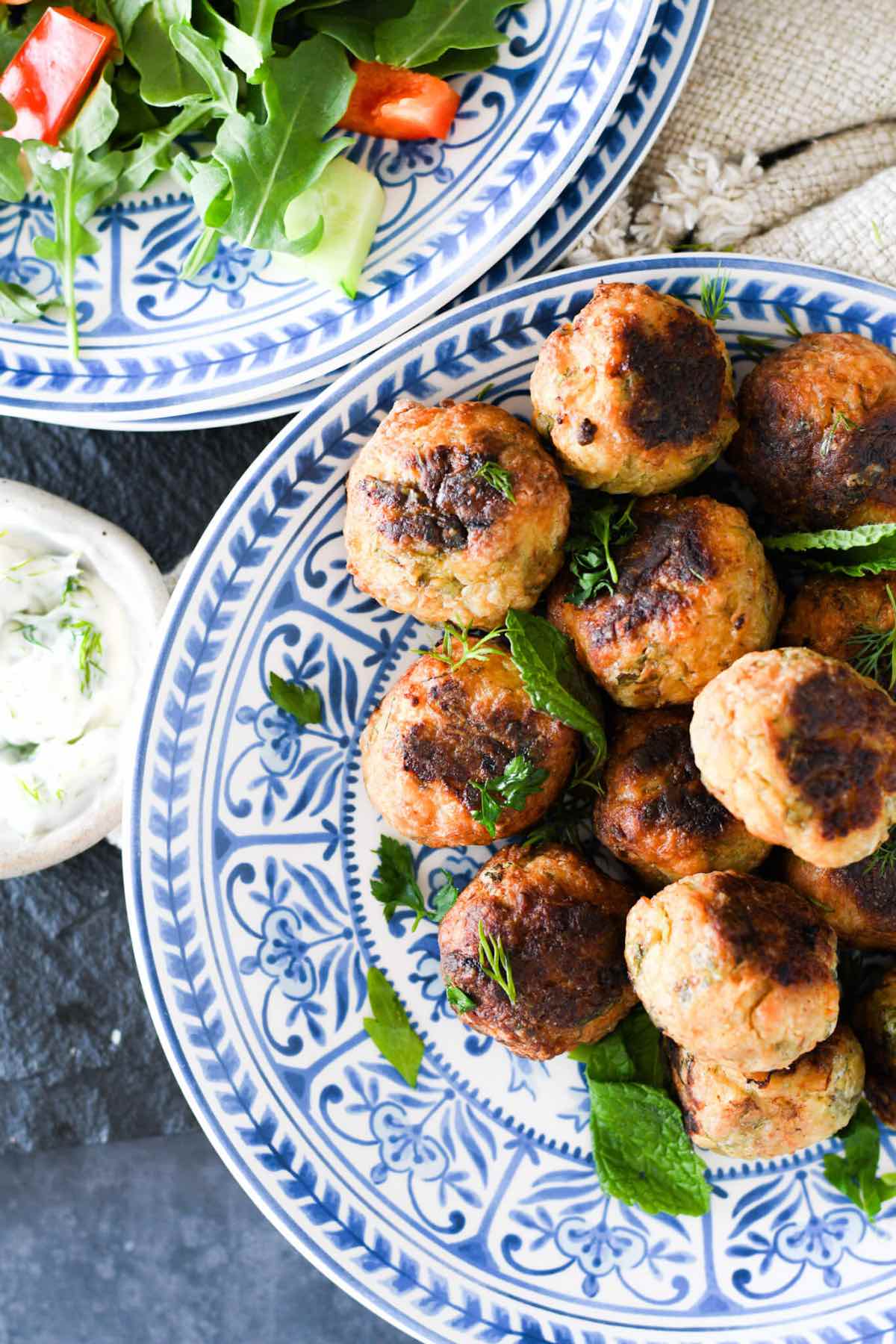 a plate of chicken keftedes on a blue plate with a side of tzatziki.